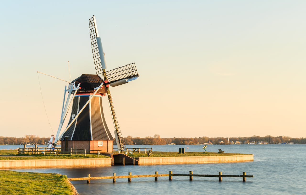 Beautiful windmill on the edge of a peaceful lake in Paterswolde at sunset.