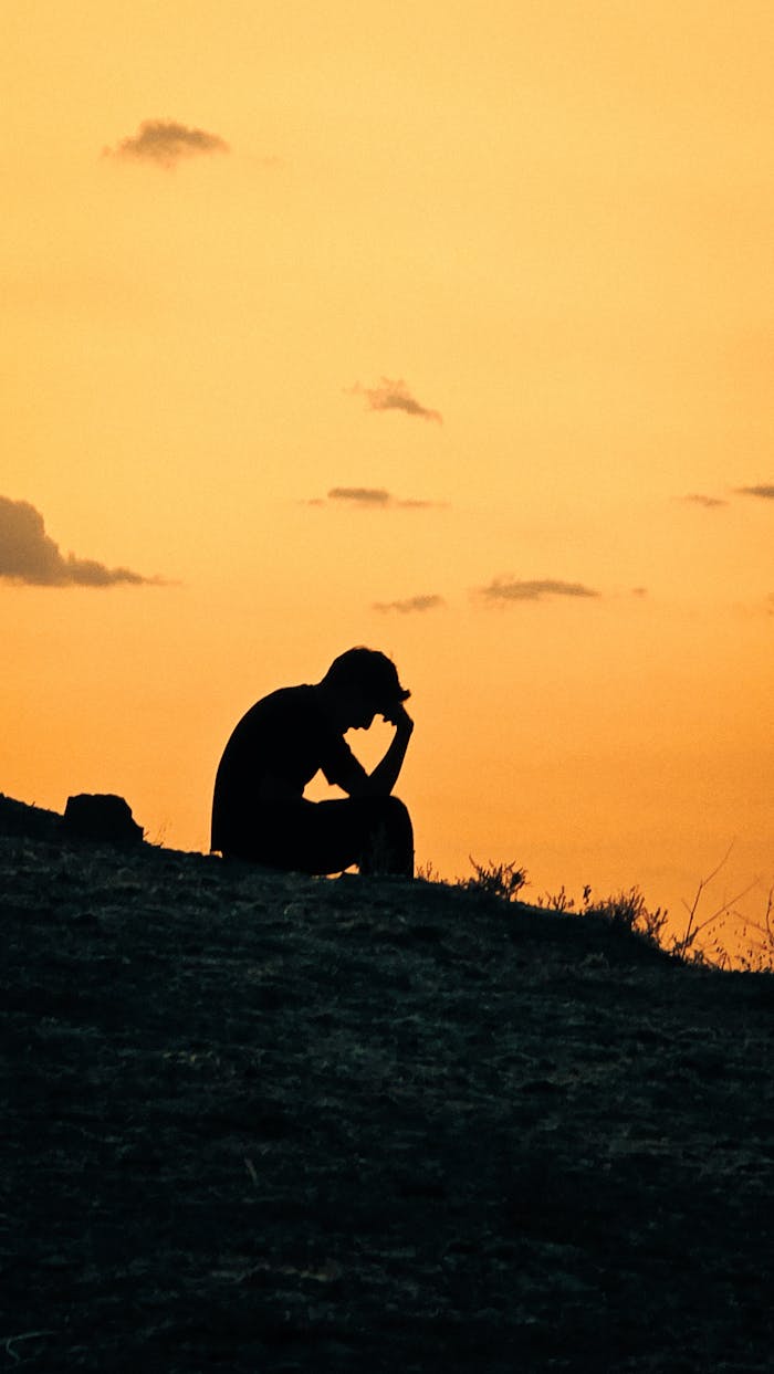 The Art of Drawing Readers In: Your attractive post title goes here Silhouette of a person sitting on a hill against a vibrant sunset sky, evoking contemplation.